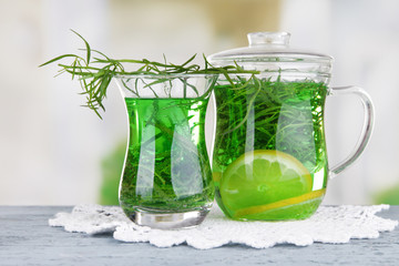 Estragon drink on napkin on wooden table on bright background
