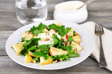 Green salad with apples, walnuts and cheese on wooden