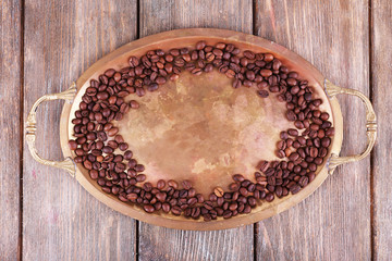 Coffee beans on metal tray on wooden background