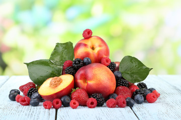 Peaches with berries on table on natural background