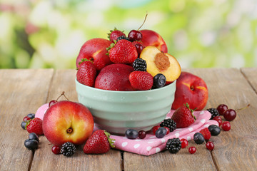 Peaches and berries in bowl on table on natural background