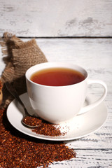 Cup of tasty rooibos tea, on old white wooden table