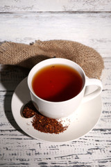 Cup of tasty rooibos tea, on old white wooden table
