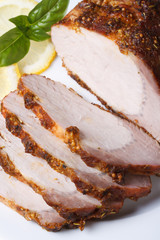 Tasty baked pork fillet and basil on a plate. vertical close up