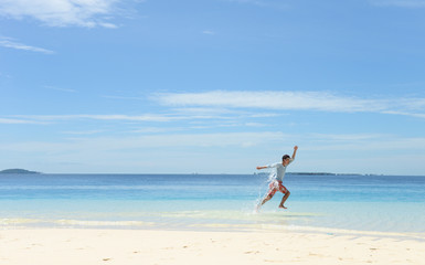 young man running in shallow water on tropical beach