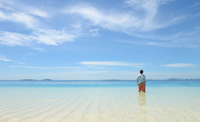 young man running in shallow water on tropical beach