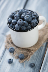 Enameled cup full of ripe blueberries, close-up, studio shot