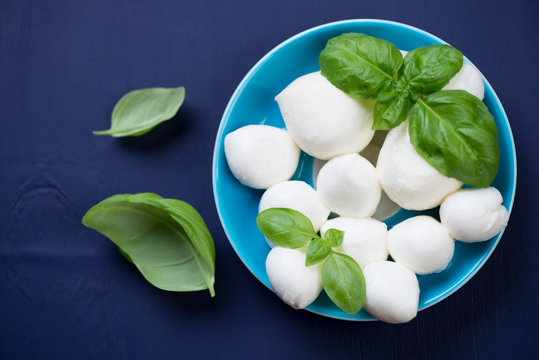 Close-up of mozzarella balls with green basil, view from above
