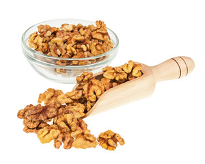 Handful of walnuts in scoop and glass bowl isolated on white.