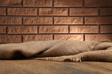 Wooden table with cloth on wall background
