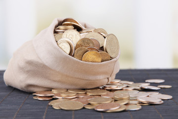 Fabric bag full of Ukrainian coins on wooden background