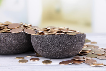 Black round plates full of Ukrainian coins on wooden table