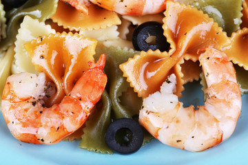 Fresh prawns with coloured macaroni and olives in a blue plate