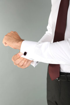 Man doing collar button up on grey background