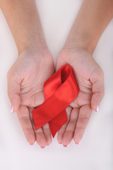 Woman with aids awareness red ribbon in hands isolated on white