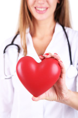 Young beautiful doctor holding red heart, close-up