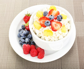 Cottage cheese with fruits and berries in bowl on table