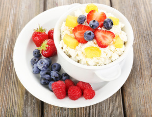 Cottage cheese with fruits and berries in bowl on wooden table