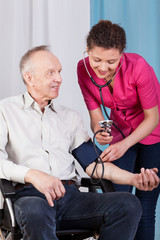 Nurse measuring blood pressure of disabled