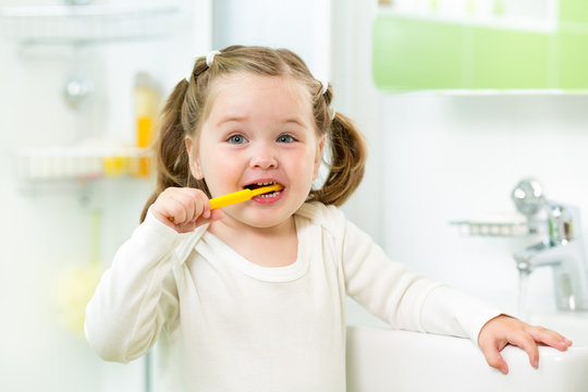 child girl brushing teeth in bathroom
