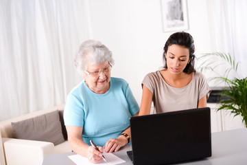 young woman helping old person for paperwork and telephone call