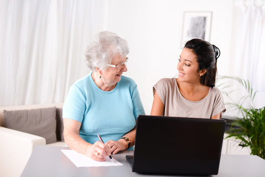 Young Woman Helping Old Person For Paperwork And Telephone Call