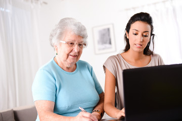 young woman helping old person for paperwork and telephone call