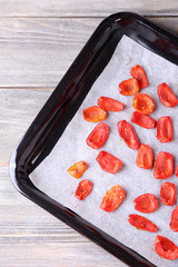 Sun dried tomatoes on drying tray, on wooden background