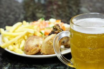 The image of meat with a garnish and mug with a beer
