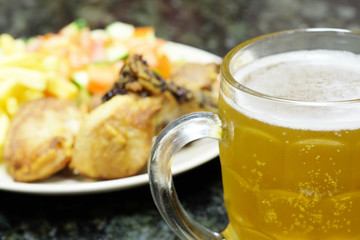 The image of meat with a garnish and mug with a beer