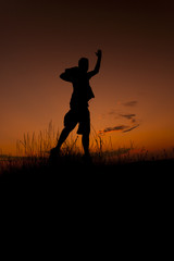 Happy man jumping. Silhouette in the sunset sky