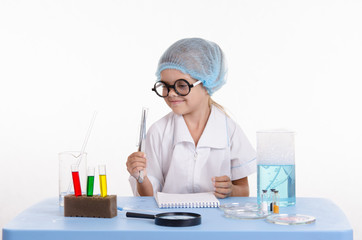 Girl chemist holding tweezers
