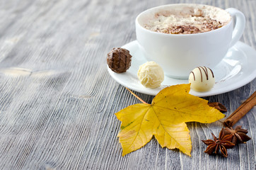 Cup of cappuccino, pralines and autumn leaves copy space