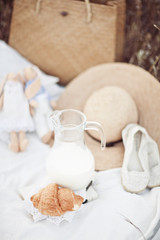 Fototapeta na wymiar Picnic detail: hat, milk, tilda, croissant, shoes on white plied