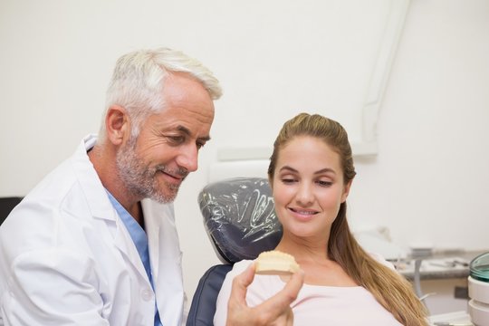 Dentist showing patient model of teeth