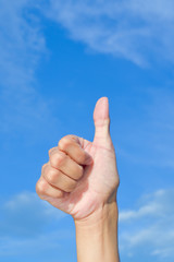 Closeup  hand thumbs up sign blue sky background