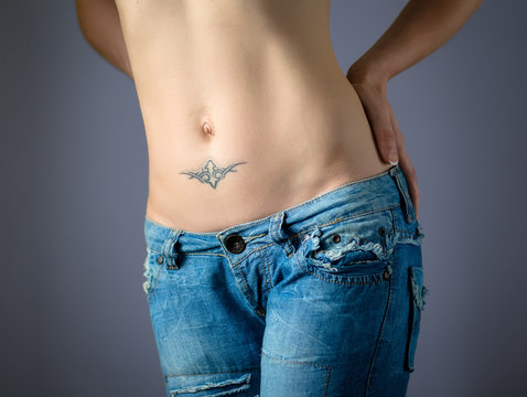 Woman's belly with tattoo in jeans