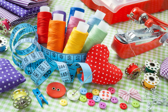 spools of colorful thread, buttons, fabrics, measuring tape, pin