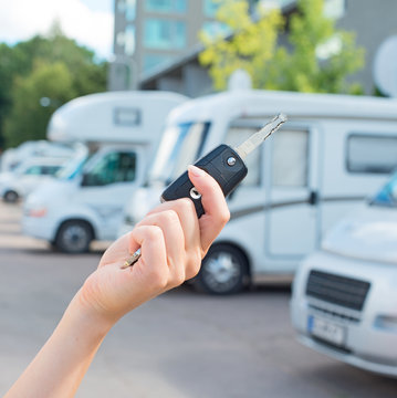 Woman's hand with key against campervans background.