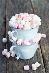marshmallows in metallic cups on wooden table