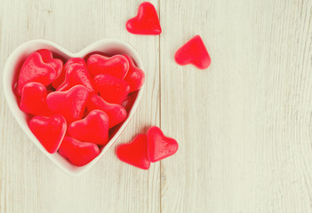 heart-shaped candies in a bowl on wooden surface