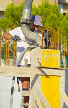 Worker pouring concrete in a construction column.