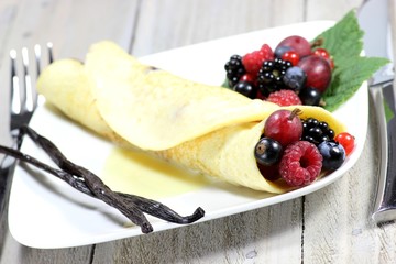 Pfannkuchen mit frischen Beeren auf Holztisch