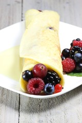 Pfannkuchen mit frischen Beeren auf Holztisch