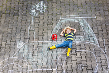 Little boy having fun with tractor picture drawing with chalk