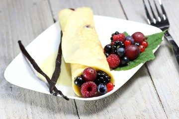 Pfannkuchen mit frischen Beeren auf Holztisch
