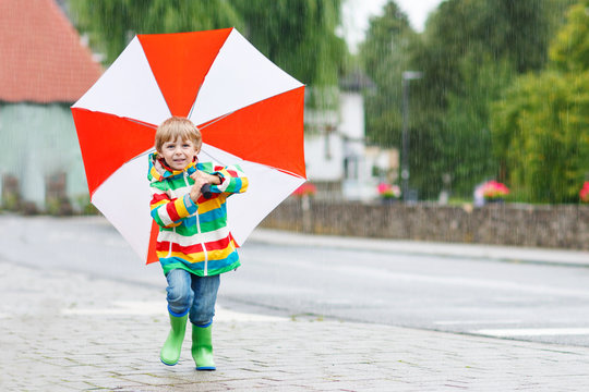 Beautiful child with yellow umbrella and colorful jacket outdoor