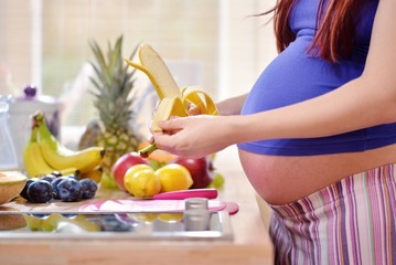 pregnant woman peeling a banana