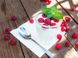 Glass of yogurt with raspberry on wooden table