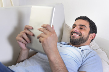 happy attractive man using digital tablet lying on couch